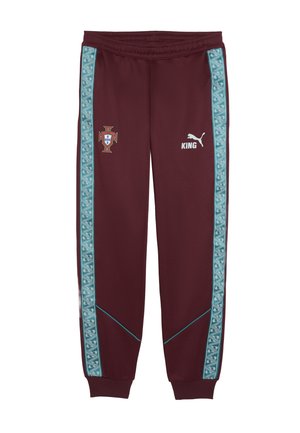 Bordeauxrote Jogginghose mit türkis gemusterten Streifen, Portugal-Emblem am linken Oberschenkel und weißem Puma-Logo mit "KING" am rechten Oberschenkel.