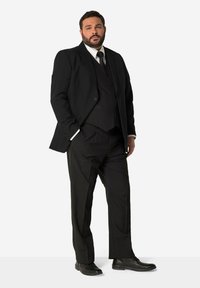 Completo da uomo nero su misura composto da giacca a un bottone, gilet coordinato e pantaloni eleganti. Completato con una camicia bianca e una cravatta nera. Scarpe da cerimonia nere.