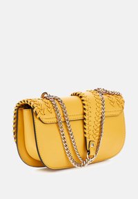 Borsa a tracolla gialla in pelle con dettagli intrecciati, forma rettangolare e tracolla in catena argentata. Texture liscia con dettagli neri.