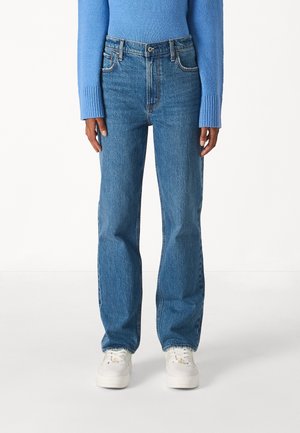 Person wearing straight-leg blue jeans with button and zipper closure, paired with white sneakers and a light blue sweater.