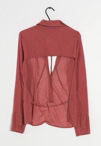 Långärmad skjorta i dämpad rosafärg, med en genomskinlig baksida, krage och knäppta manschetter, samt en unik utskärning på baksidan.