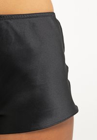 Zwarte zwembroek van glad, glanzend nylon. Beschikt over een comfortabele tailleband en een korte snit met strakke randen. Getextureerde stof.