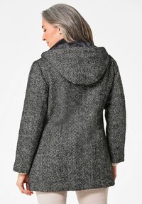 Textuur houndstooth jas in zwart-wit met een capuchon, met een middellange snit en contrasterende voering. Gladde afwerking en gestructureerd ontwerp.