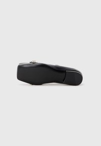 Black flat shoe with a rounded toe, smooth leather upper, and a low, sturdy heel. Features a small decorative metal accent on the upper.