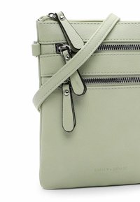 Grüne Leder-Crossbody-Tasche mit silbernen Reißverschlüssen, ausgestattet mit mehreren Reißverschlussfächern und einer glatten Textur. Verstellbarer Gurt inklusive.