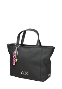 Musta olkalaukku, joka on valmistettu sileästä synteettisestä materiaalista, kahdella kahvalla. Laukussa on hopeinen logo ja värikkäitä avaimenperäkoristeita.