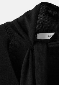 Maglione nero in maglia caratterizzato da una texture morbida, scollo aperto e marcati dettagli di cucitura al colletto e all'area delle spalle.