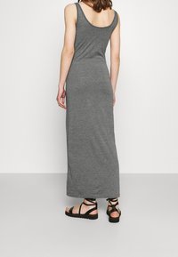 Gray, sleeveless maxi dress with a scoop back; made of soft, stretchy fabric. Paired with black strappy sandals.