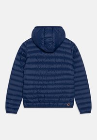 Chaqueta acolchada tipo puffer azul marino con capucha, mangas largas y puños elásticos, vista desde la parte de atrás sobre un fondo blanco.