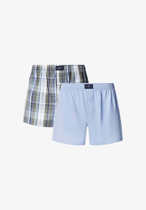 Kaksi miesten bokseriparia: toinen vihreän ja sinisen ruutukuviolla, toinen yksivärinen vaaleansininen. Molemmissa on joustovyötärö ja napit.