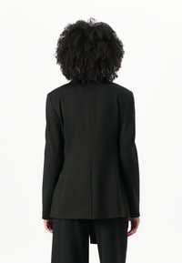 Zwarte op maat gemaakte blazer met een rechte snit, lange mouwen en een achterkantopening, gemaakt van een gladde stof. Heeft een minimalistisch ontwerp zonder versieringen.
