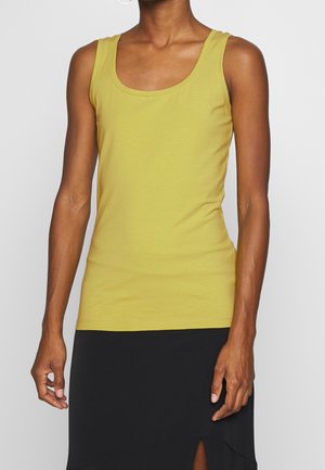 Limettengrünes Tanktop aus weichem Stoff, mit rundem Ausschnitt und ärmellosem Design, kombiniert mit einem schwarzen Rock.