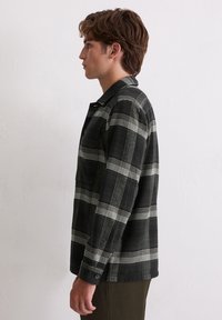 Zwart-witte geruite flanellen shirt met een kraag, knoopsluiting aan de voorkant en lange mouwen. Zachte textuur en een ontspannen pasvorm.