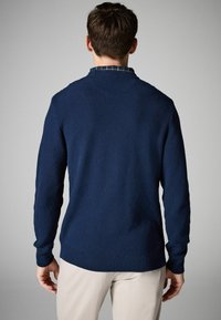 Pulover tricotat navy cu țesătură texturată, decolteu rotund și manșete cu nervuri, având o fanta mică pe lateral la tiv.