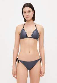 Sivý bikiny set s trojuholníkovým vrchom a čierno-bielym lemovaním. Spodná časť má viazacie strany pre prispôsobenie a hladkú textúru.