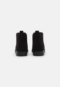 Black suede ankle boots with a smooth finish, round toe, and low block heel. Features pull tabs on the back for easy wearing.