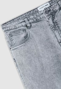 Jeans in denim grigio con un classico design a cinque tasche, texture sbiadita e orlo sfrangiato. Include una chiusura con bottone e dettagli di cucitura visibili.