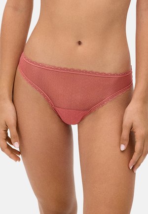 Mujer vistiendo ropa interior tipo bikini de malla transparente con encaje rosa y patrón de puntos, mostrada desde la mitad del torso hasta la parte superior de los muslos.