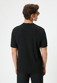 Sort tekstureret kortærmet t-shirt med rund hals, med diskrete prægede mønstre og en afslappet pasform.