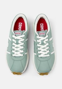 Light green sneakers with white accents and laces, featuring a cushioned red insole and a textured rubber sole.
