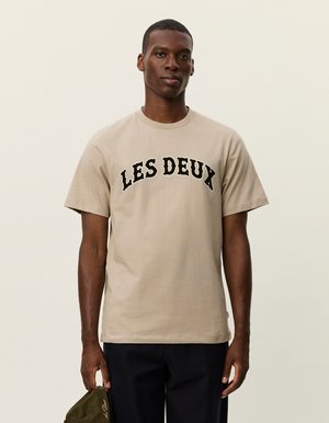 T-shirt beige en coton à manches courtes, col rond, avec "LES DEUX" imprimé en lettres en arc noires sur la poitrine.