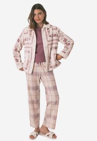 Leichte Jacke mit floralem Muster aus weichem Stoff, kombiniert mit einem einfarbigen lila Oberteil und karierter Hose in Pastellfarben sowie Hausschuhen. Lässiger Loungewear-Look.