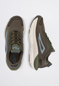 Scarpe da ginnastica verde scuro con tomaia in rete, dettagli blu chiaro, suola testurizzata e collo imbottito. Presentano lacci rotondi e un logo prominente.