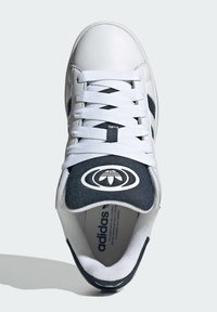 Adidași albi cu accente bleumarin, design cu șireturi, talpă texturată și un logo proeminent pe limbă, cu laterale perforate.