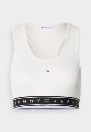 Valge soonikkoega spordirinnahoidja ümarate lõigetega ja racerback-disainiga. Sellel on must rihm "TOMMY JEANS" logoga ning ees on väike tikitud logo.