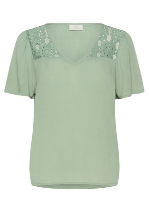 Blouse verte avec un décolleté en V, des manches courtes bouffantes et des détails en dentelle sur les épaules. Fabriquée en tissu doux avec une coupe ample.