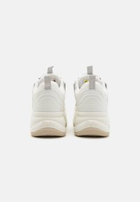 Baskets de sport blanches et gris clair avec une finition texturée, une forme arrondie, un talon renforcé et un logo de marque subtil en relief sur la semelle.