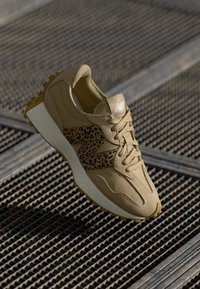 Brune atletiske sko med leopardskinnselement på siden, teksturert stoff, gummisåle og snøredesign, som viser en moderne silhuett.