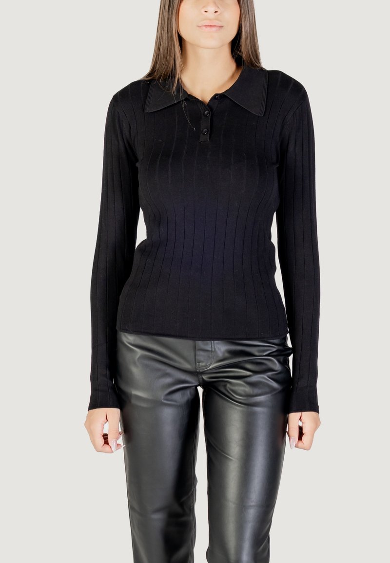 Polo nero a maniche lunghe con coste, colletto e pattina con tre bottoni, abbinato a pantaloni in pelle nera lucida. Texture liscia e design aderente.