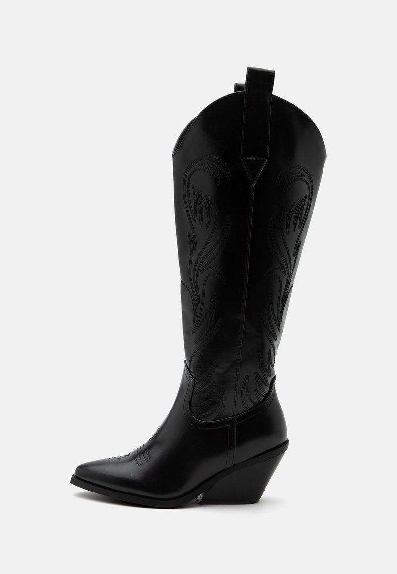 Botte de cowboy en cuir noir avec bout pointu, talon bloc incliné, couture décorative et languettes en haut sur fond blanc.