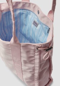 Roze tote bag met een zachte, gestructureerde buitenkant, voorzien van een lichtblauwe gevoerde binnenkant met strepen en een ritszak. Verstelbare trekkoordsluiting.