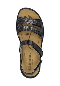 Musta sandaali, jossa on kolme leveää hihnaa ja pehmeä vaaleanbeige pohja. Hihnoissa on teksturoitu muotoilu ja pohjassa on logotieto.