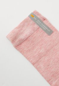 Roze katoenen sokken met een gestructureerd patroon, voorzien van een omgeslagen boord en een label met de tekst "zonder compressie."