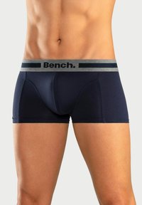 Temno modri bokserice z gumirico v sivi barvi, na kateri je logotip "Bench." Narejene iz mehke, raztegljive tkanine z oprijetim dizajnom.