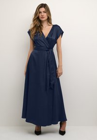 Navy blue wrap dress with a deep V-neck, short cap sleeves, and a tie belt, made from smooth fabric, featuring a flowing skirt and floor length.