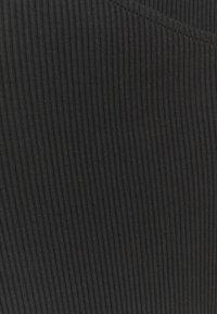 Tissu noir à côtes avec des lignes verticales, présentant une texture douce et un matériau légèrement extensible, idéal pour les designs ajustés.