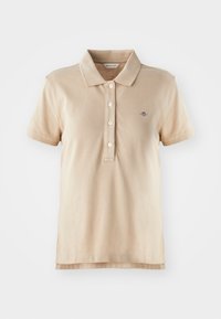 Beige poloskjorte laget av bomull, med klassisk krage, tre knappestolper, korte ermer og en liten brodert logo på brystet.