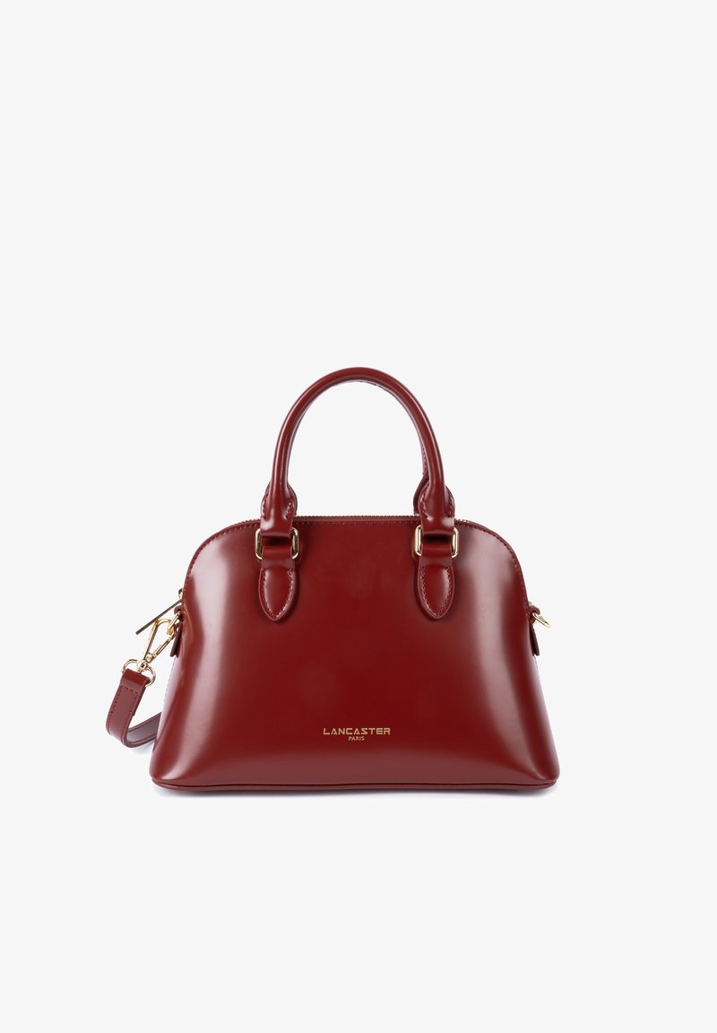 Borsa a mano in pelle rossa lucida con due manici arrotondati, dettagli in metallo dorato e spallacci rimovibili. Presenta una chiusura con zip.