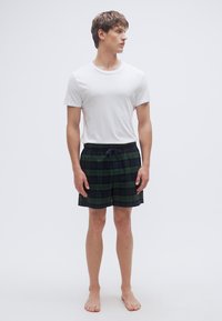 Βαμβακερά καρό σορτς σε πράσινο και ναυτικό μπλε, με ελαστική μέση και κορδόνι ρύθμισης. Φορεμένα με απλό λευκό μπλουζάκι με στρογγυλή λαιμόκοψη.