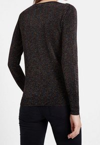 Pull noir à manches longues avec un tricot texturé, présentant des éclats multicolores partout. Silhouette ajustée, encolure ronde simple et ourlet côtelé.