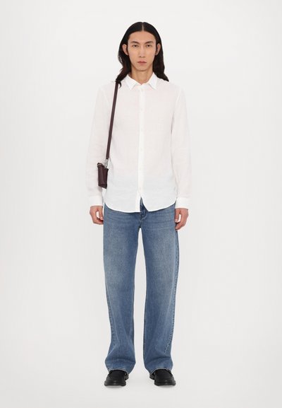 White long-sleeve button-up shirt, faded blue wide-leg jeans, black shoes, and a small brown shoulder bag positioned over the shoulder.