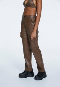 Bruine nepleer cargobroek met zijzakken, een relaxed fit en een zachte textuur, gecombineerd met chunky zwarte platform schoenen.