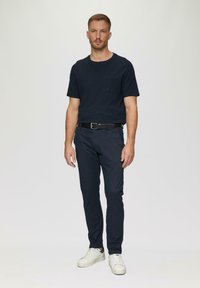 Marine crew-neck t-shirt met zak, gecombineerd met marine slim-fit chino's en witte sneakers. Soepele stof, casual ontwerp, minimalistische accenten.
