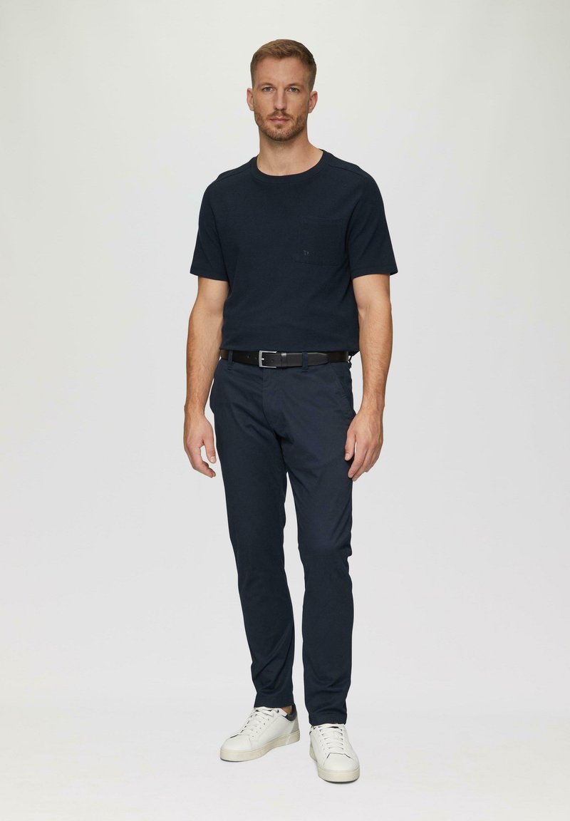 Marine crew-neck t-shirt met zak, gecombineerd met marine slim-fit chino's en witte sneakers. Soepele stof, casual ontwerp, minimalistische accenten.