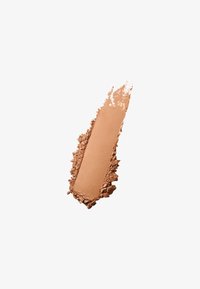 Bronceador en polvo compacto en tono bronceado cálido, con textura suave y acabado mate, rodeado de escamas de polvo suelto, sobre un fondo blanco.