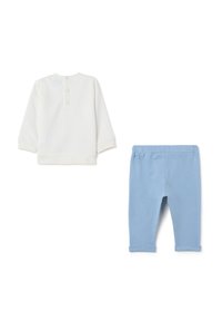 Witte lange mouwen top met knopen op de rug en lichtblauwe elastische taille legging, beide gemaakt van zacht katoen.